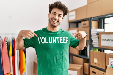 Yardım merkezinde gönüllü üniforma için parmaklarını gösteren genç bir İspanyol.