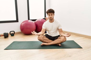 Genç İspanyol adam spor merkezinde yoga eğitimi alıyor.