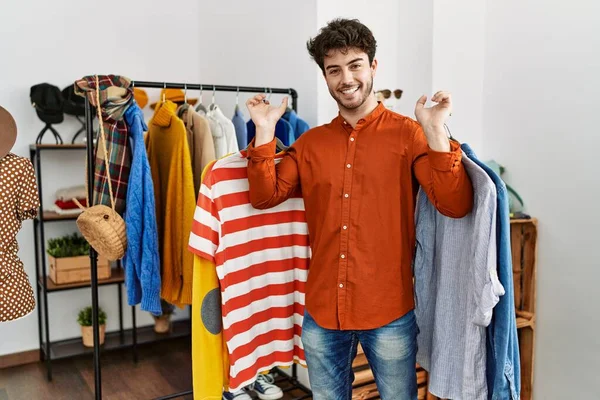 Joven Cliente Hispano Sonriendo Feliz Sosteniendo Ropa Tienda Ropa — Foto de Stock