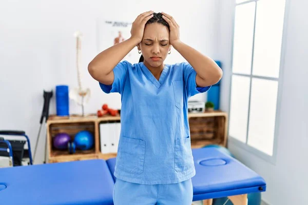 在疼痛康复诊所工作的年轻的非洲裔美国妇女 由于疼痛和偏头痛 绝望和压力重重 手放在头上 — 图库照片