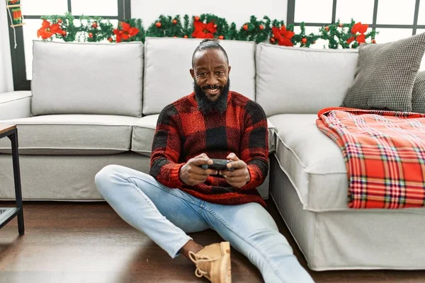 年轻的非洲裔美国人坐在家里的圣诞装饰品旁玩电子游戏 — 图库照片
