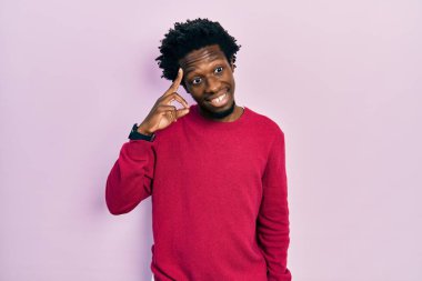 Gündelik giysiler giymiş genç Afro-Amerikalı bir adam tek parmakla kafasını işaret ediyor, harika bir fikir ya da düşünce, iyi bir hafıza 
