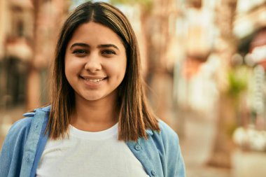 Genç Latin kız gülümseyerek şehirde mutlu mesut dikiliyor..