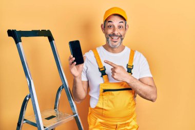 Yakışıklı, orta yaşlı, gri saçlı, merdivenin kenarında duran akıllı telefonu çılgın kutlamalar yaparken gösteren ve başarı için hayrete düşmüş, heyecanlı çığlıklar atan bir adam.. 