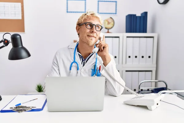 Młody Biały Mężczyzna Mundurze Lekarza Rozmawiający Przez Telefon Klinice — Zdjęcie stockowe