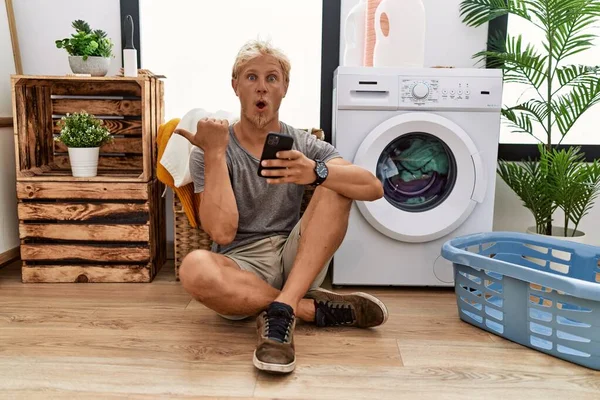 Junger Blonder Mann Wäscht Mit Smartphone Überrascht Und Zeigt Mit — Stockfoto