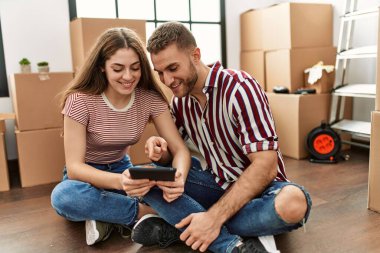 Yeni evimizde akıllı telefon kullanarak mutlu bir şekilde gülümseyen beyaz bir çift..