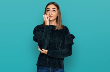 Zarif bir kazak giyen güzel esmer kadın gergin ve gergin görünüyor. Elleri ağızdan tırnak yiyor. anksiyete. 