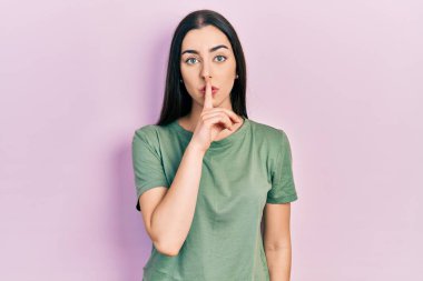 Mavi gözlü, rahat tişörtlü, sessiz olmak isteyen dudaklı güzel bir kadın. sessizlik ve gizli konsept. 