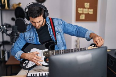 Genç İspanyol adam müzik stüdyosunda elektro gitar çalıyor.