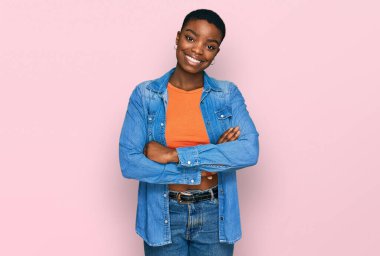 Sıradan kıyafetler giyen, kollarını kavuşturup kameraya gülümseyen genç Afrikalı Amerikalı kadın. pozitif kişi. 