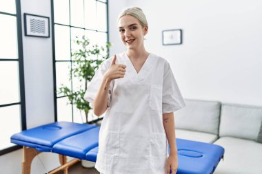 Genç Kafkas fizyoterapist kadın evde mutlu ve olumlu bir şekilde çalışıyor, başparmağı mükemmel ve onay işareti yapıyor. 