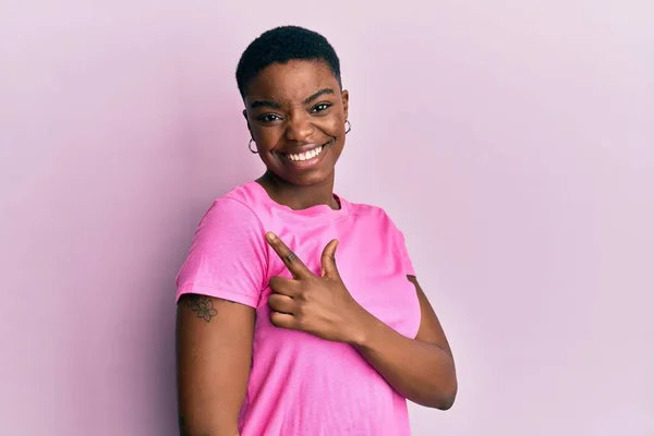 Молодая Африканская Американка Непринужденной Розовой Футболке Улыбается Веселым Указанием Рукой — стоковое фото