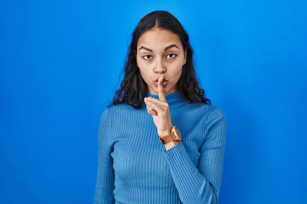 年轻的巴西女人站在蓝色孤立的背景上 要求安静 手指放在嘴唇上 沉默和秘密概念 — 图库照片