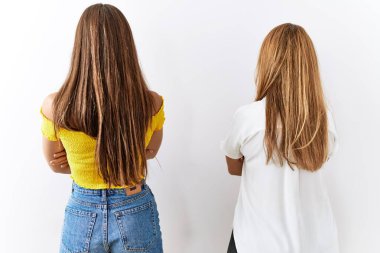 Anne ve kızı birlikte soyutlanmış arka planda yan yana durup kollarını kavuşturarak geriye bakıyorlar. 