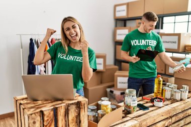 Bağışlarda gönüllü tişört giyen genç kadın ve erkek gururla ayakta duruyor zaferi ve başarıyı kutluyorlar. 