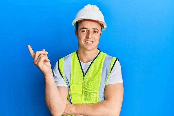 Knappe Jongeman Met Een Veiligheidshelm Een Reflecterend Jasje Glimlachend Wijzend — Stockfoto