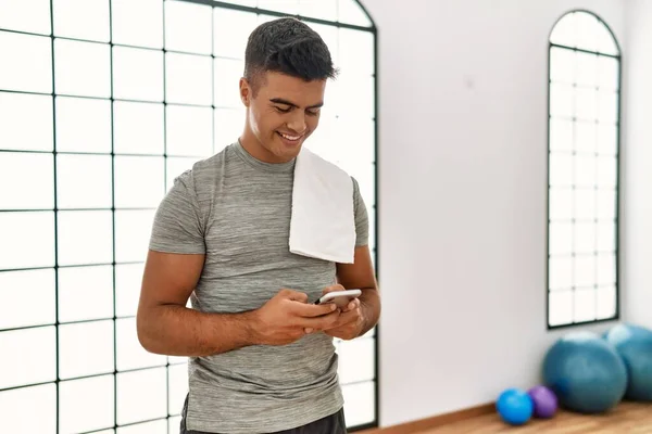 若いヒスパニック男はスポーツセンターでスマートフォンを使用して自信を笑顔 — ストック写真