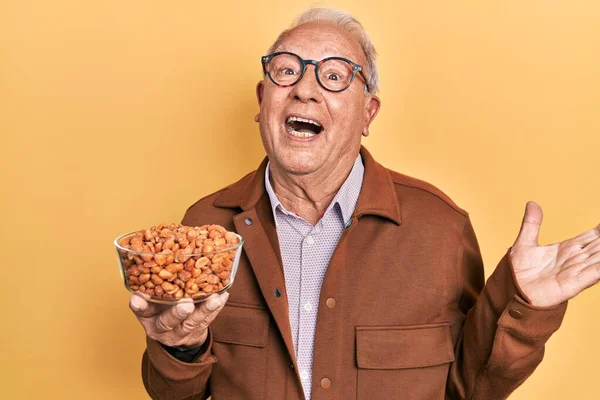 Hombre Mayor Con Pelo Gris Sosteniendo Cacahuetes Fritos Celebrando Logro —  Fotos de Stock