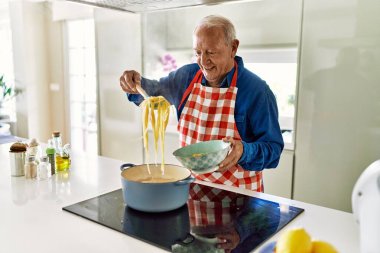Son sınıf öğrencisi, mutfakta spagetti pişirme konusunda kendinden emin gülümsüyor.