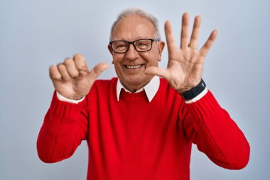 İzole edilmiş arka planda duran yaşlı adam altı numaralı parmaklarını gösterip gülümserken kendinden emin ve mutlu görünüyor.. 