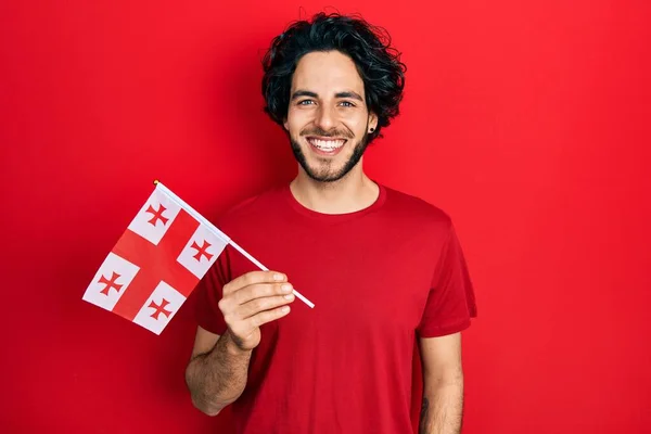 Snygg Latinamerikansk Man Håller Georgia Flagga Ser Positiv Och Glad — Stockfoto