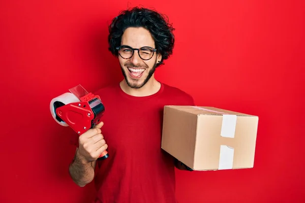 Knappe Spaanse Man Met Verpakkingstape Kartonnen Doos Die Knipoogt Naar — Stockfoto