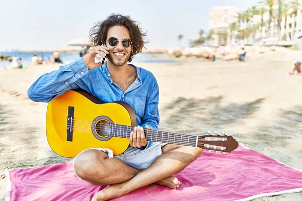 年轻的他的惊慌失措的男人在沙滩上弹奏吉他 在智能手机上聊天 — 图库照片