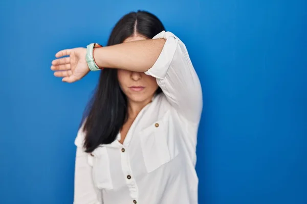 Mulher Hispânica Jovem Sobre Fundo Azul Cobrindo Olhos Com Braço — Fotografia de Stock