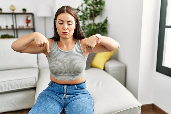 Jonge Brunette Vrouw Zitten Bank Thuis Wijzen Naar Beneden Kijken — Stockfoto