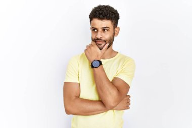 Arap genç bir adam izole edilmiş arka planda durup kameraya kollarını kavuşturup gülümseyerek ve çenesini kaldırarak bakıyor. Olumlu düşünmek. 