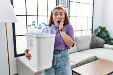 Genç kızıl saçlı kadın elinde plastik şişelerle çöp sepetini tutuyordu. Korkmuş ve şok olmuştu. Şaşırmış ve şaşırmış bir haldeydi. 