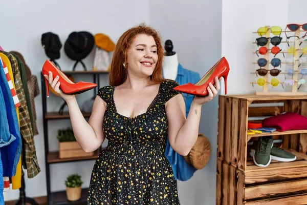 Genç kızıl saçlı kadın, yüksek topuklu ayakkabı mağazasından alışveriş yapıyor.