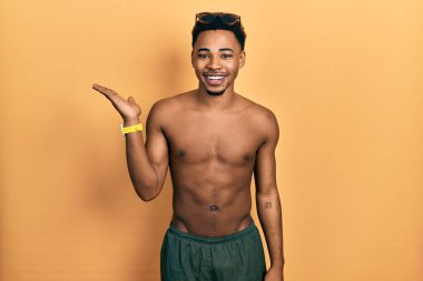 Mayo ve yüzme gözlüğü takan genç Afro-Amerikalı adam mutlu bir şekilde gülümseyerek avucunun içinde kameraya bakıyor.. 