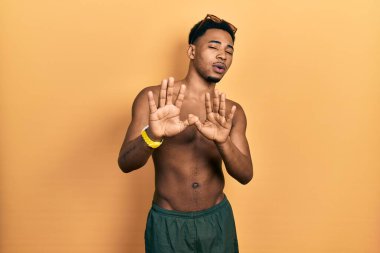 Mayo ve yüzücü gözlüğü takan genç Afro-Amerikalı adam avuç içlerini hareket ettiriyor. Korkmuş ve iğrenç bir ifadeyle reddediyor. Dur ve yasakla. 