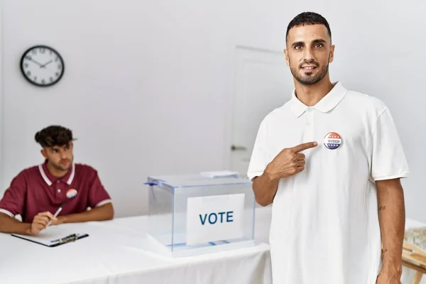 Jovem Eleitor Hispânico Apontando Com Dedo Crachá Centro Eleitoral — Fotografia de Stock