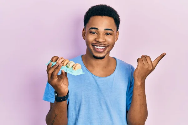 Jonge Afro Amerikaanse Man Houdt Macarons Vrolijk Wijzend Met Hand — Stockfoto