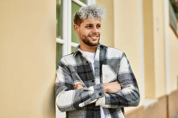 Genç İspanyol adam mutlu bir şekilde gülümsüyor şehirde çapraz hareketlerle.