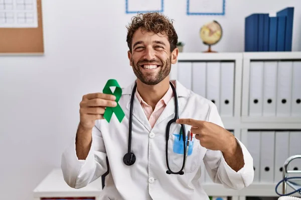 Joven Médico Hispano Sosteniendo Cinta Verde Apoyo Clínica Señalando Con — Foto de Stock