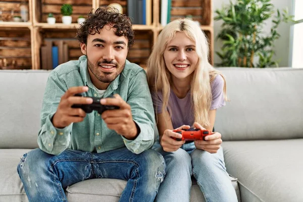 年轻夫妇开心地笑着在家里玩电子游戏 — 图库照片
