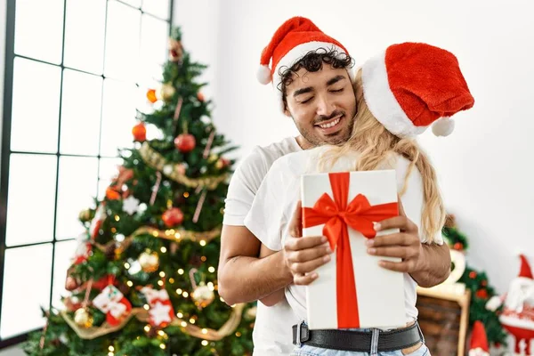 Νεαρό Ζευγάρι Φοράει Χριστουγεννιάτικο Καπέλο Αγκαλιάζει Και Κρατώντας Δώρο Στο — Φωτογραφία Αρχείου