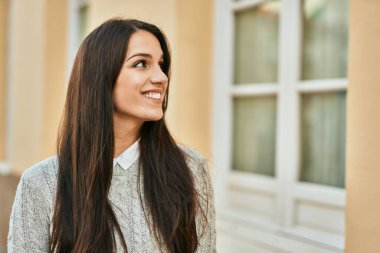 Genç İspanyol kadın gülümseyerek şehirde mutlu mesut dikiliyor..