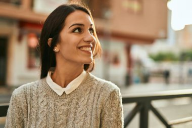 Genç İspanyol kadın gülümseyerek şehirde mutlu mesut dikiliyor..