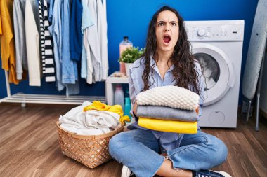 Genç esmer kadın temiz çamaşırları tutuyor kızgın ve kızgın çığlık atıyor sinirli ve öfkeli, öfkeyle bağırıyor.. 