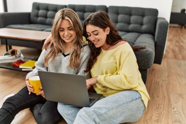 Genç çift dizüstü bilgisayarlarını kullanarak mutlu bir şekilde gülümsüyor..