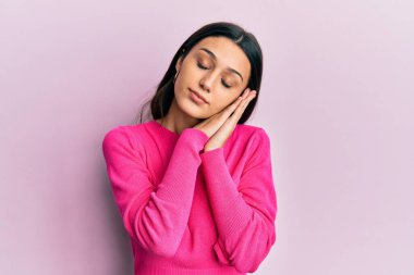 Latin kökenli genç bir kadın gündelik kıyafetler giyip uyuyordu. Yorgun düşler görüyordu. Elleriyle poz veriyordu.. 