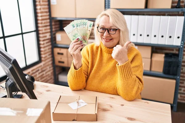 Orta yaşlı, beyaz bir kadın elinde Hong Kong dolarlarıyla küçük bir şirkette çalışıyor. Gülümsüyor, gülümsüyor ve olumlu bakıyor. 