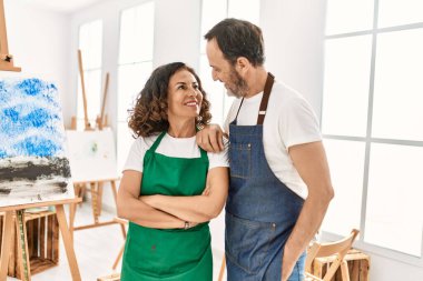 Sanat stüdyosunda mutlu mutlu gülümseyen iki orta yaşlı öğrenci..