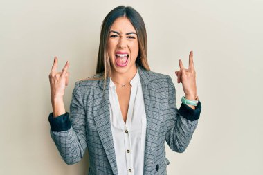 İş kıyafetleri giymiş, çılgın bir ifadeyle bağıran genç İspanyol kadın elleri havada rock sembolü yapıyor. Müzik yıldızı. ağır kavram. 