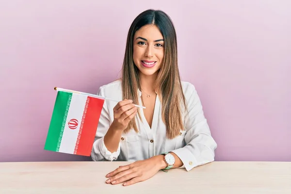 Jovem Hispânica Segurando Bandeira Iran Sentado Mesa Olhando Positivo Feliz — Fotografia de Stock